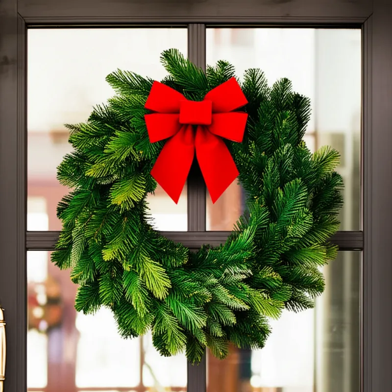 Vòng nguyệt quế trang trí cửa kính Noel với nơ đỏ và lá thông tươi, mang vẻ đẹp truyền thống.